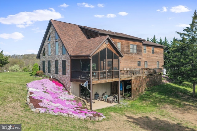back of property featuring a yard, a sunroom, a wooden deck, and a patio area