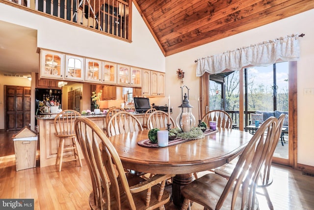 dining room with high vaulted ceiling, wooden ceiling, and light wood-type flooring