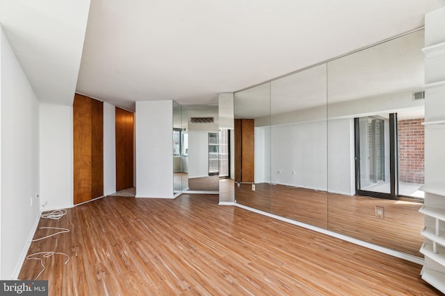 unfurnished living room with baseboards, visible vents, and wood finished floors