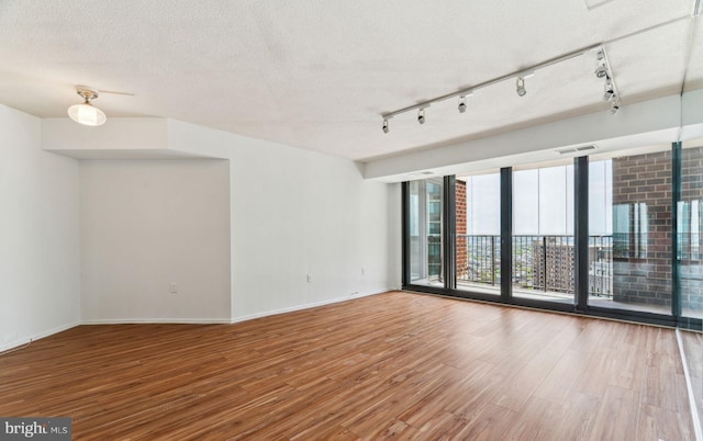 spare room with baseboards, visible vents, wood finished floors, and expansive windows