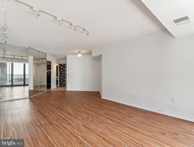 unfurnished room featuring visible vents, baseboards, track lighting, and light wood-type flooring