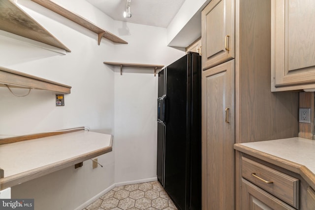 interior space featuring open shelves, light countertops, baseboards, black refrigerator with ice dispenser, and light tile patterned flooring