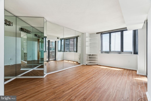 unfurnished room with baseboards, wood finished floors, a healthy amount of sunlight, and visible vents