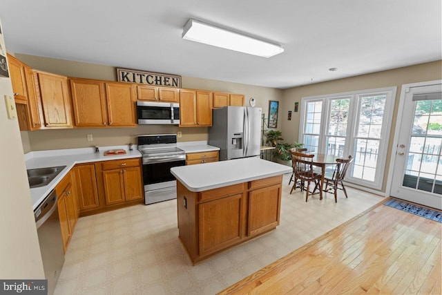 kitchen featuring a sink, stainless steel appliances, a center island, light countertops, and light floors