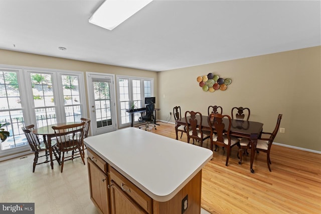 kitchen with baseboards, brown cabinetry, light countertops, and a kitchen island