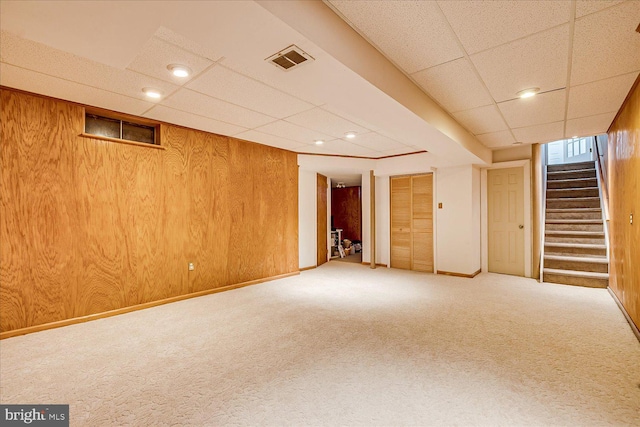 basement featuring carpet flooring, stairs, visible vents, and a paneled ceiling