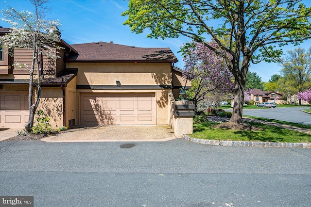 exterior space featuring a garage, driveway, and stucco siding