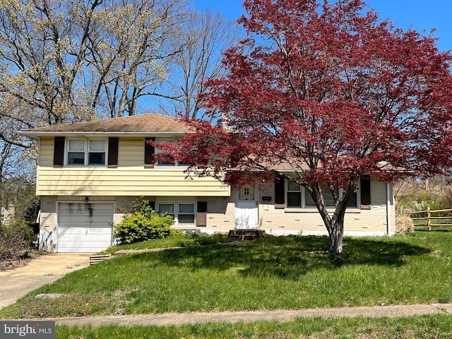 view of front of home featuring a garage, fence, a front yard, brick siding, and driveway