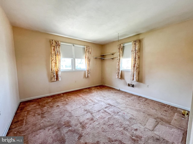 carpeted spare room with baseboards, plenty of natural light, and visible vents