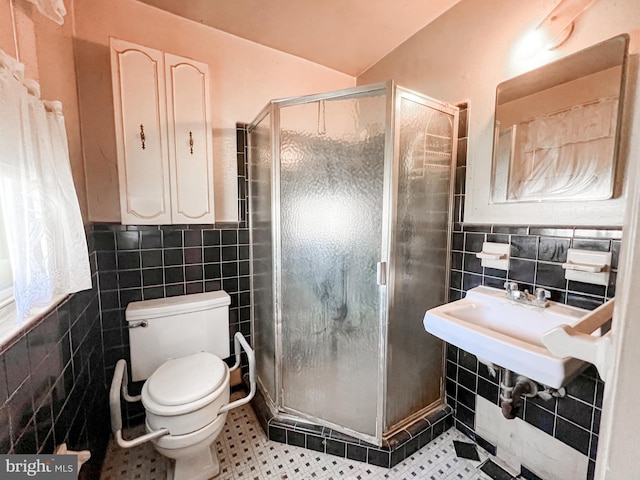full bath with tile walls, a shower stall, tile patterned floors, a wainscoted wall, and toilet