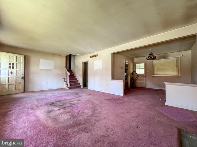 unfurnished living room featuring visible vents, carpet flooring, stairs, and baseboards