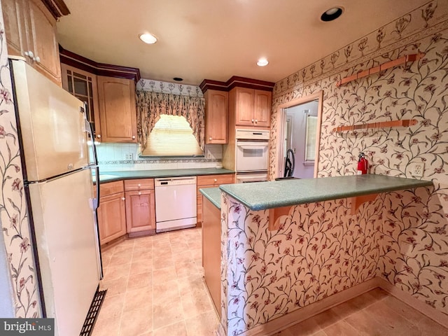 kitchen featuring a peninsula, dark countertops, white appliances, wallpapered walls, and recessed lighting