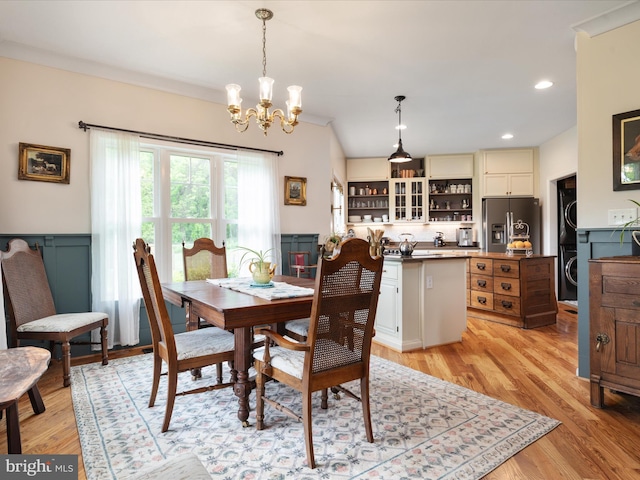 dining room featuring stacked washing maching and dryer, a chandelier, and light wood-style flooring
