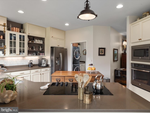 kitchen featuring recessed lighting, open shelves, dark countertops, stainless steel appliances, and stacked washer / drying machine