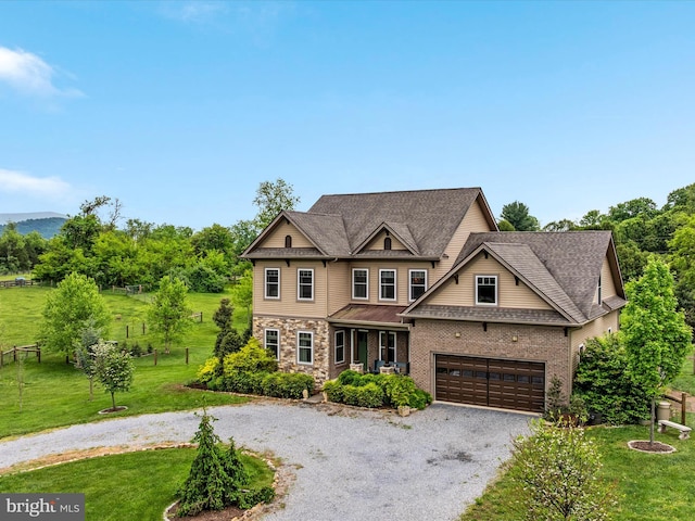 craftsman-style home featuring driveway, a front yard, an attached garage, stone siding, and roof with shingles