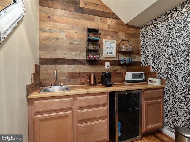 bar featuring beverage cooler, indoor wet bar, a sink, wood walls, and vaulted ceiling