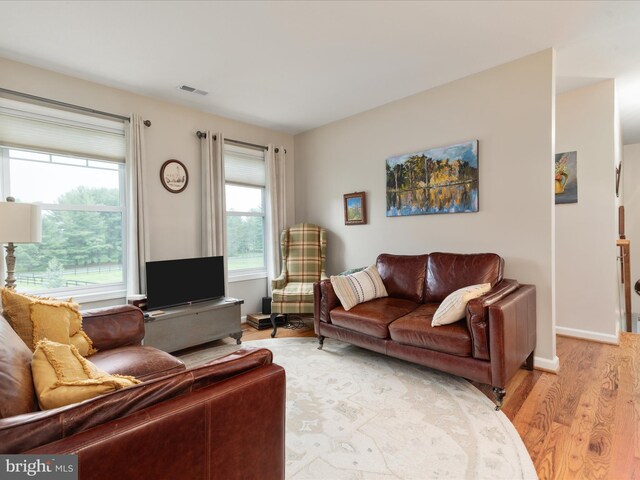 living room featuring baseboards, light wood finished floors, and visible vents