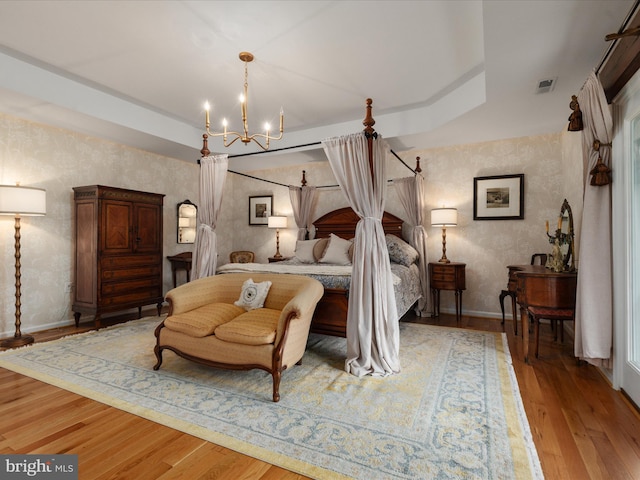 bedroom with baseboards, light wood-style floors, an inviting chandelier, and visible vents