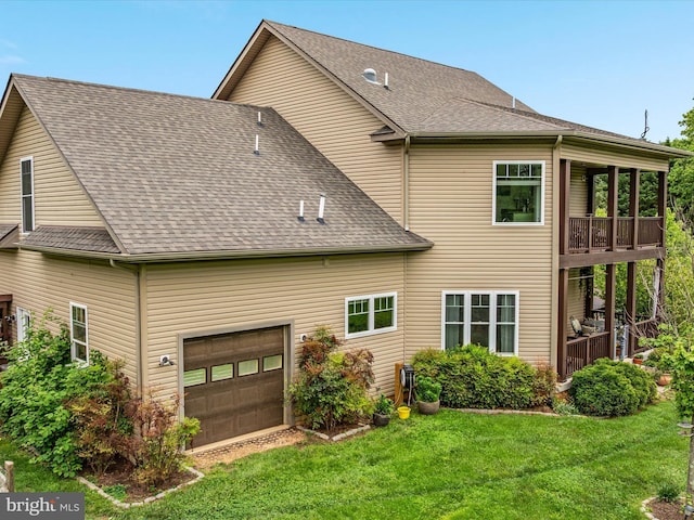 rear view of house featuring a shingled roof, a yard, and a garage