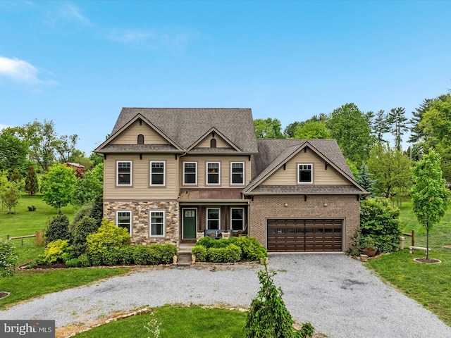 craftsman-style house featuring an attached garage, a shingled roof, a front yard, a porch, and gravel driveway