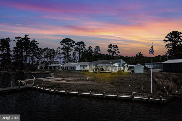 back of house at dusk featuring an outdoor structure and a water view