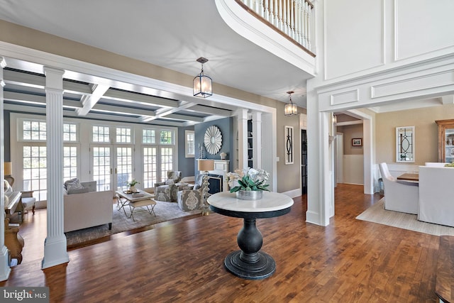 living room with ornate columns, wood finished floors, coffered ceiling, beamed ceiling, and a chandelier