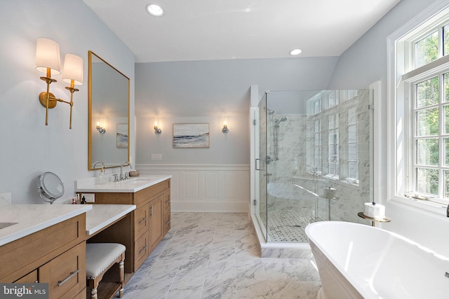 bathroom with a stall shower, two vanities, a freestanding bath, recessed lighting, and marble finish flooring
