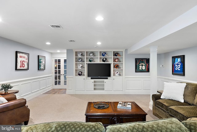 living area featuring light carpet, a decorative wall, recessed lighting, and wainscoting