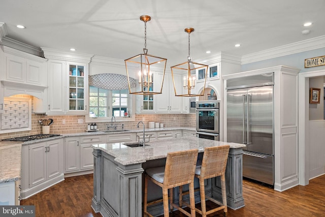 kitchen featuring appliances with stainless steel finishes, a sink, dark wood-style floors, white cabinets, and crown molding