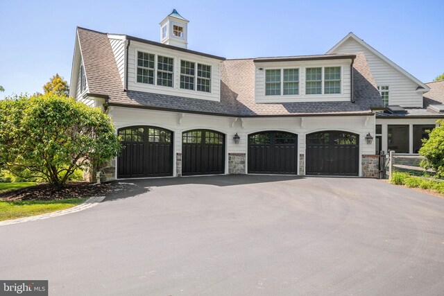 view of front of house featuring asphalt driveway, stone siding, an attached garage, and a shingled roof
