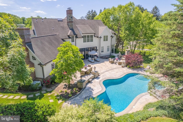 rear view of house featuring a patio area, an outdoor pool, a fenced backyard, a chimney, and roof with shingles
