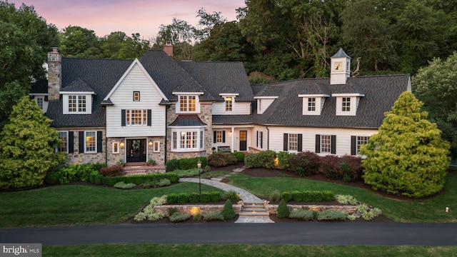 view of front of property with a chimney, stone siding, and a front lawn