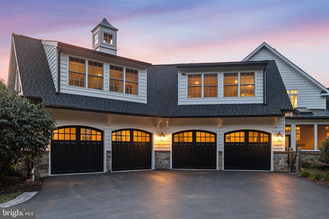 shingle-style home featuring a garage, stone siding, asphalt driveway, and a shingled roof