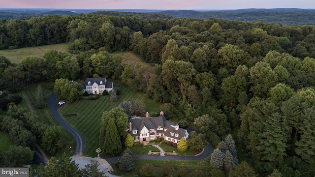 aerial view of property and surrounding area featuring a heavily wooded area