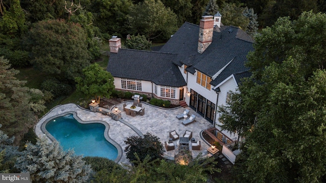 aerial view of property and surrounding area with a pool area and a heavily wooded area