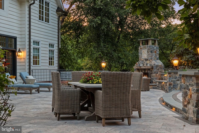 patio terrace at dusk with an outdoor stone fireplace and outdoor dining space