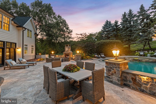 view of patio featuring an outdoor stone fireplace, a pool with connected hot tub, and outdoor dining space