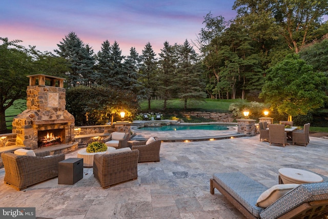 pool at dusk featuring a patio area, an outdoor pool, and an outdoor living space with a fireplace