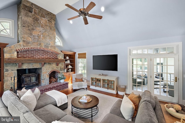 living area with a ceiling fan, wood finished floors, a large fireplace, and high vaulted ceiling