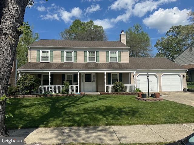 view of front of house featuring a chimney, an attached garage, driveway, a porch, and a front yard