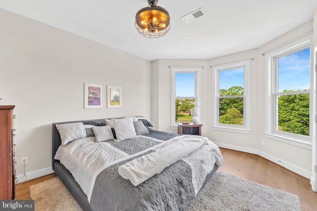 bedroom with visible vents, light wood finished floors, and baseboards