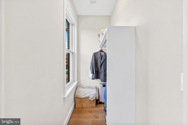 walk in closet with wood finished floors