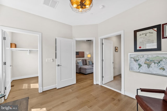 interior space featuring a chandelier, visible vents, light wood-style floors, and a closet