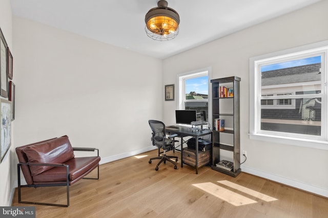 office featuring baseboards, a notable chandelier, and light wood finished floors