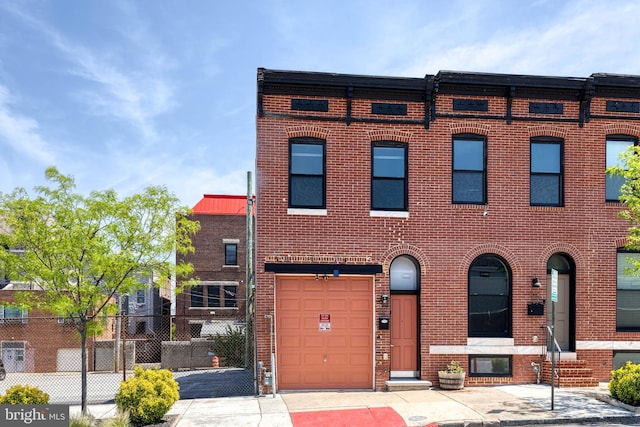 view of property with fence, an attached garage, and brick siding