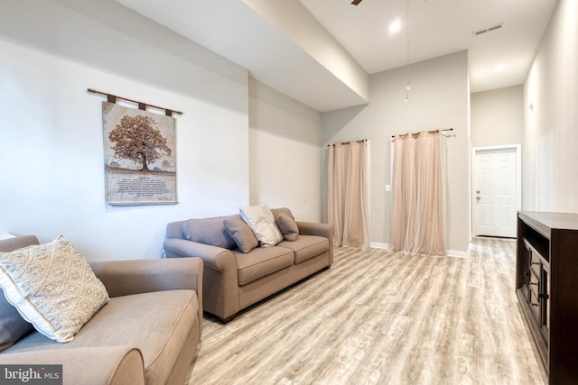 living room featuring a ceiling fan, baseboards, visible vents, and light wood-type flooring