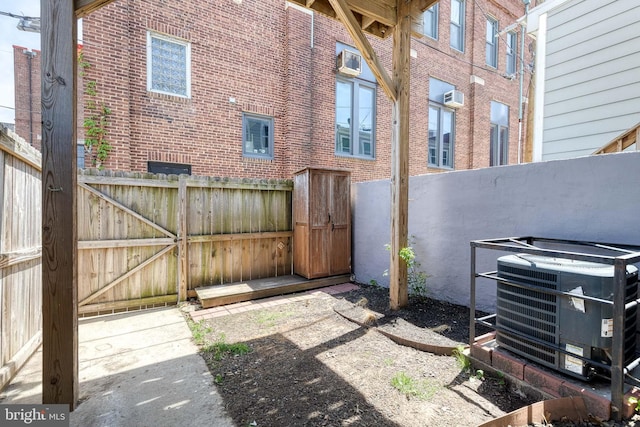 view of yard with central AC unit, a gate, a fenced backyard, and an AC wall unit