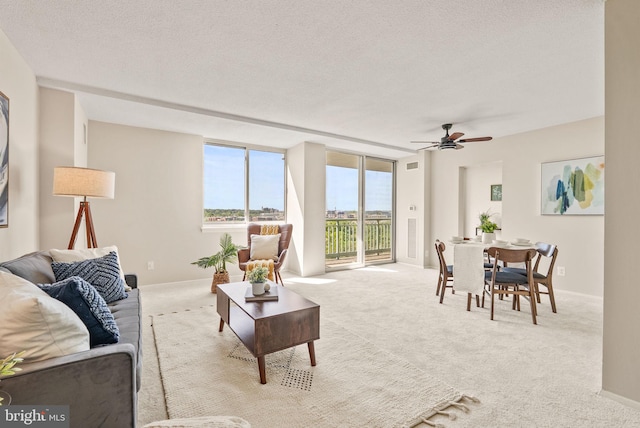 living area with baseboards, a ceiling fan, a textured ceiling, and carpet
