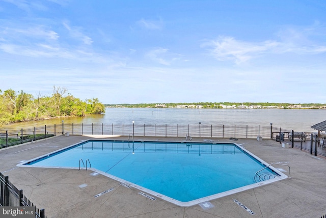 community pool with fence and a water view