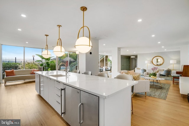 kitchen featuring light wood finished floors, open floor plan, a kitchen island with sink, and a sink